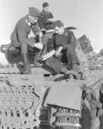 El radioperador de un Panzer III de la 16.ª División Panzer le enseña a un oficial de la Luftwaffe la munición del carro de combate.