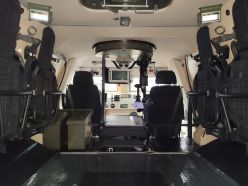 Interior del mismo vehículo. Se puede ver el puesto del operador de la estación de armas remota, con un asiento plegable, un panel de control con pantalla y una palanca de mando.