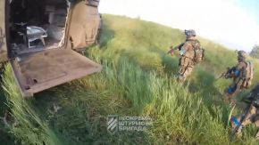 Soldados de la 3.ª Brigada de Asalto Azov de las Fuerzas Terrestres de Ucrania avanzando en el campo de batalla detrás de la protección de un M113 a finales de julio de 2023.