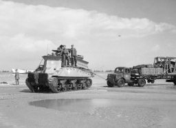 Un vehículo de recuperación Sherman BARV remolcando camiones en la playa Gold.