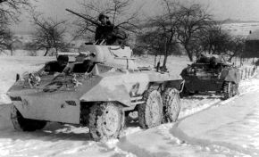En esta imagen tomada en diciembre de 1944 durante la Batalla de las Ardenas vemos a dos M8, el primero con camuflaje invernal y el segundo con camuflaje de verano. También podemos apreciar las cadenas en las ruedas.
