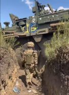 Stryker atascado en una zanja no muy ancha a finales de agosto de 2023 en el área de Robotyne. El impacto hizo que perdiera algún eje y aparentemente tiene los laterales cubiertos con troncos.[9]